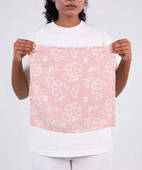 Person holding a pink floral textured fabric with white patterns against a white background