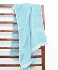 Light blue towel draped over a wooden towel rack on a white background