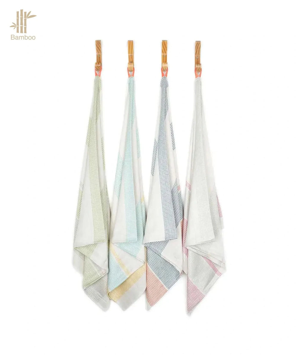 Four bamboo towels hanging on a rack with a white background