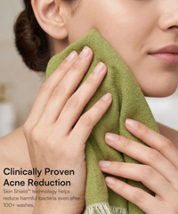 Close-up of woman gently pressing a green Doctor Towels face towel against her cheek.