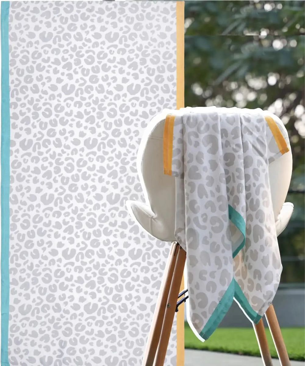 Leopard print towel draped over a chair with a patterned wall in the background