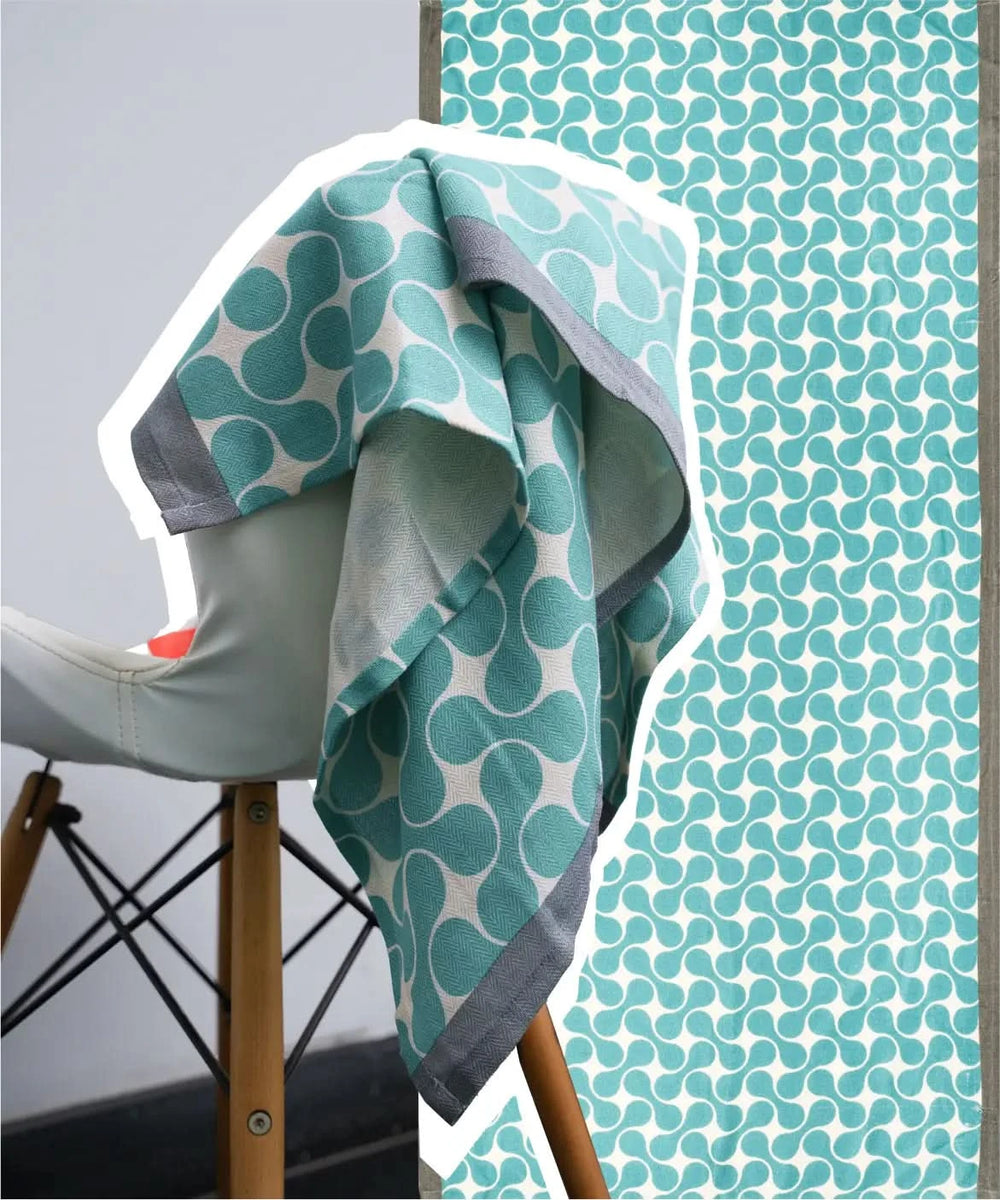 Teal and white patterned towel draped over a chair with a close-up of the pattern on a gray background.