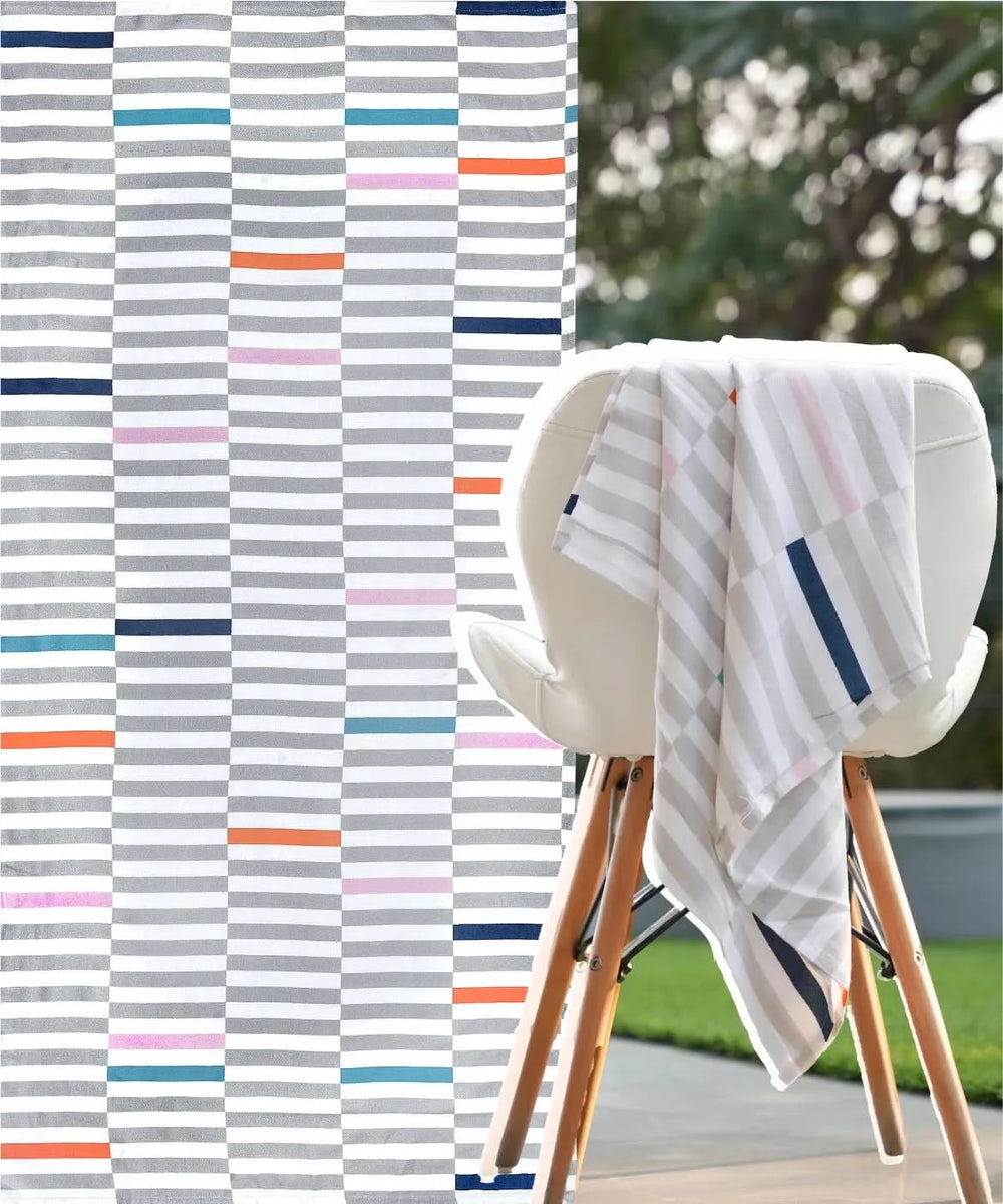 Piano Pop Bamboo Bath towel with multicolor pattern draped over a chair outdoors.