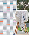 Piano Pop Bamboo Bath towel with multicolor pattern draped over a chair outdoors.