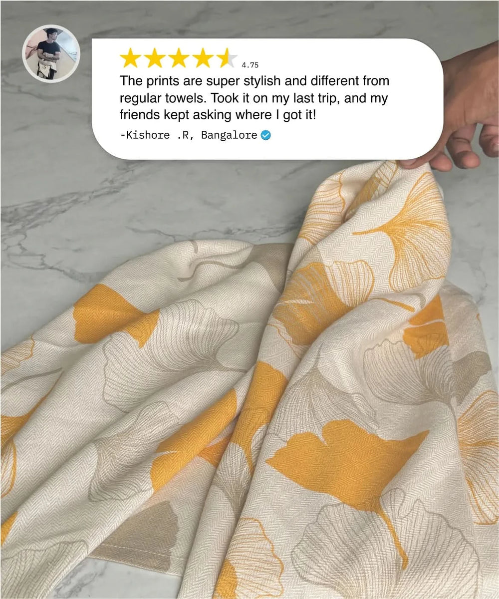 Floral-patterned towel with a hand holding it, featuring a customer review on a marble surface.