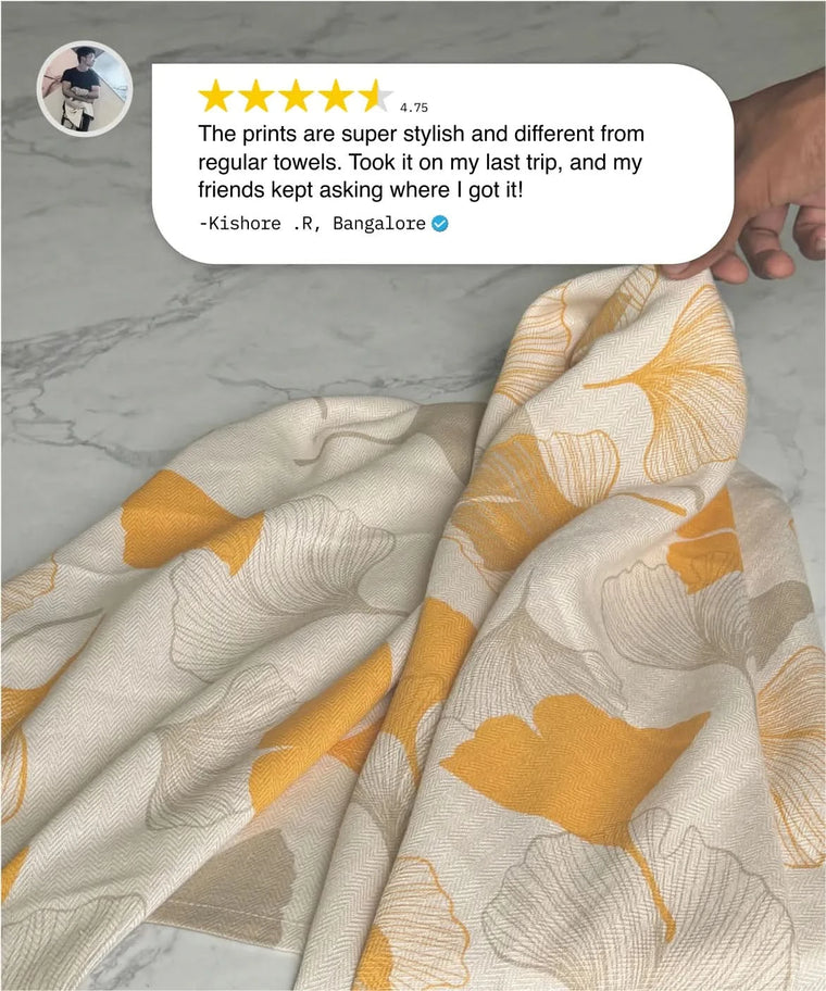 Floral-patterned towel with a hand holding it, featuring a customer review on a marble surface.