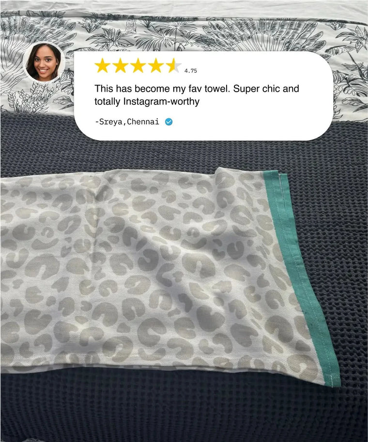 Leopard print towel with green border on a textured surface, featuring a customer review.