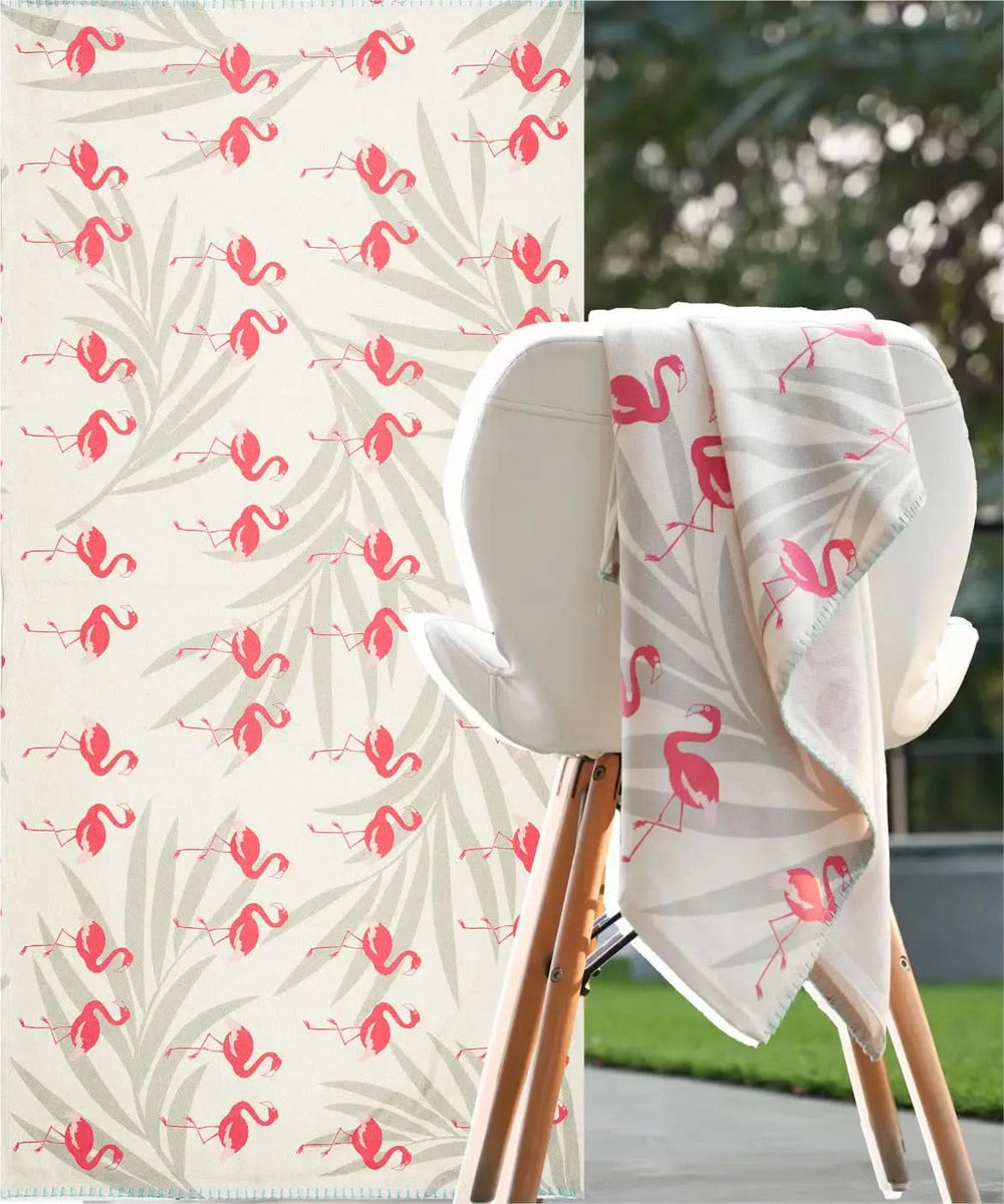 Floral-patterned towel with pink flamingo design draped over a chair outdoors.