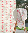 Floral-patterned towel with pink flamingo design draped over a chair outdoors.
