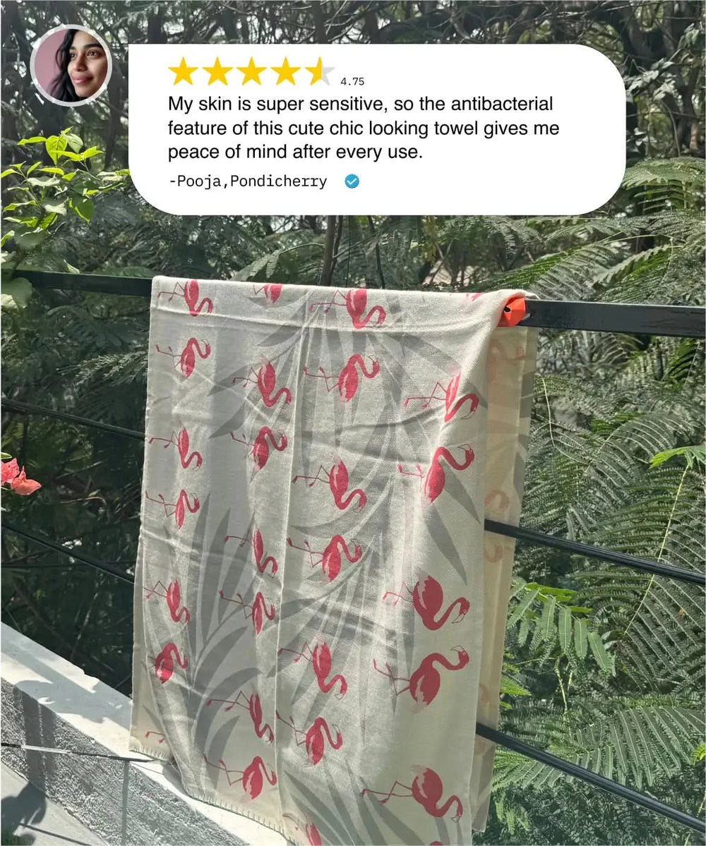 Towel with flamingo pattern hanging on a rack with a review above it.