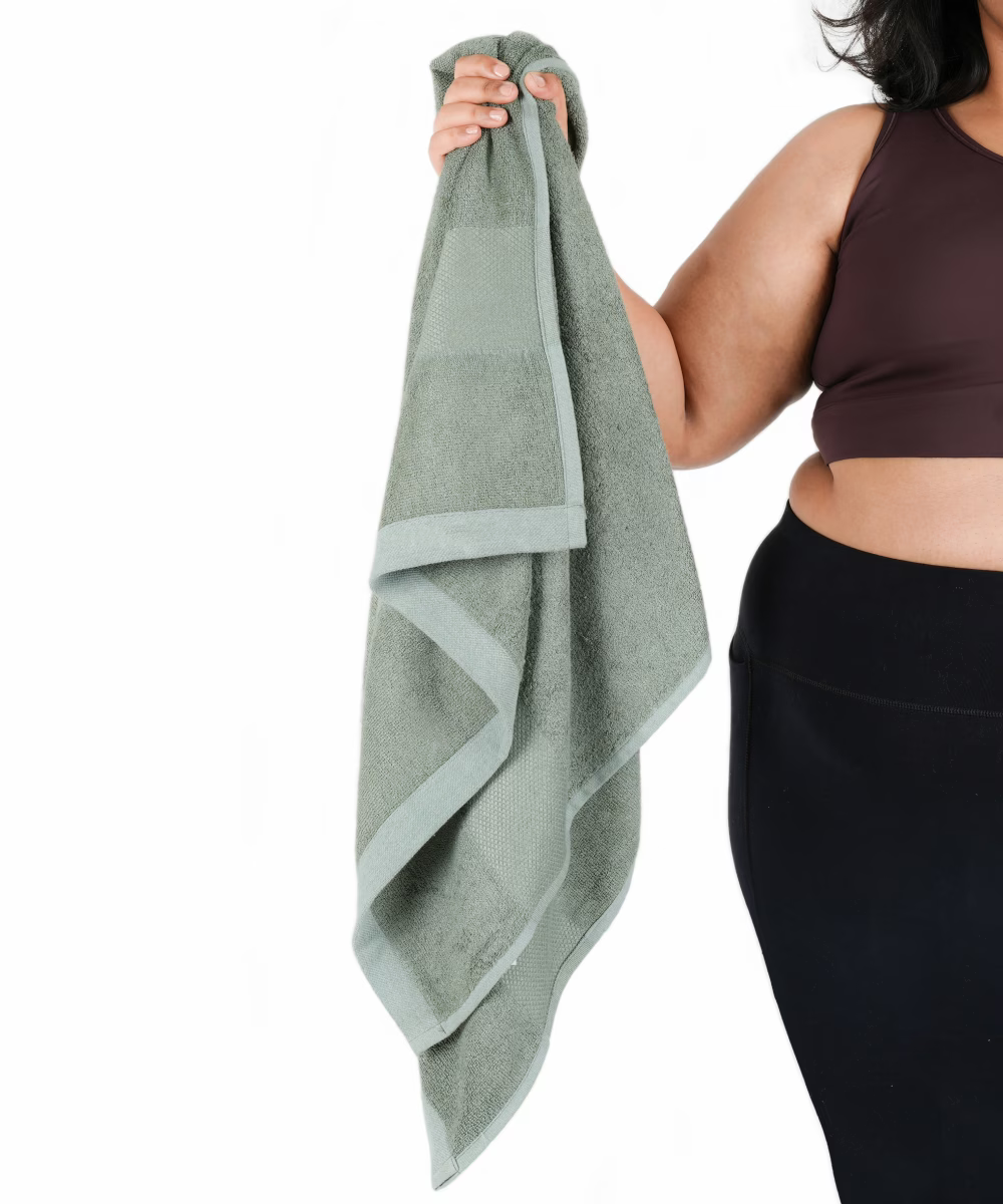 Person holding a sage green towel with a white background