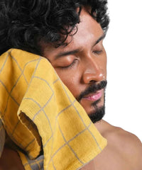 Man with a yellow towel on his head against a white background