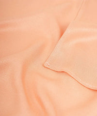 Close-up of peach-colored fabric with a subtle texture