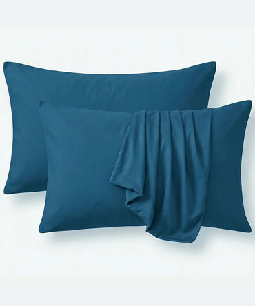 Two mirage blue pillows with a fitted sheet draped over them on a white background