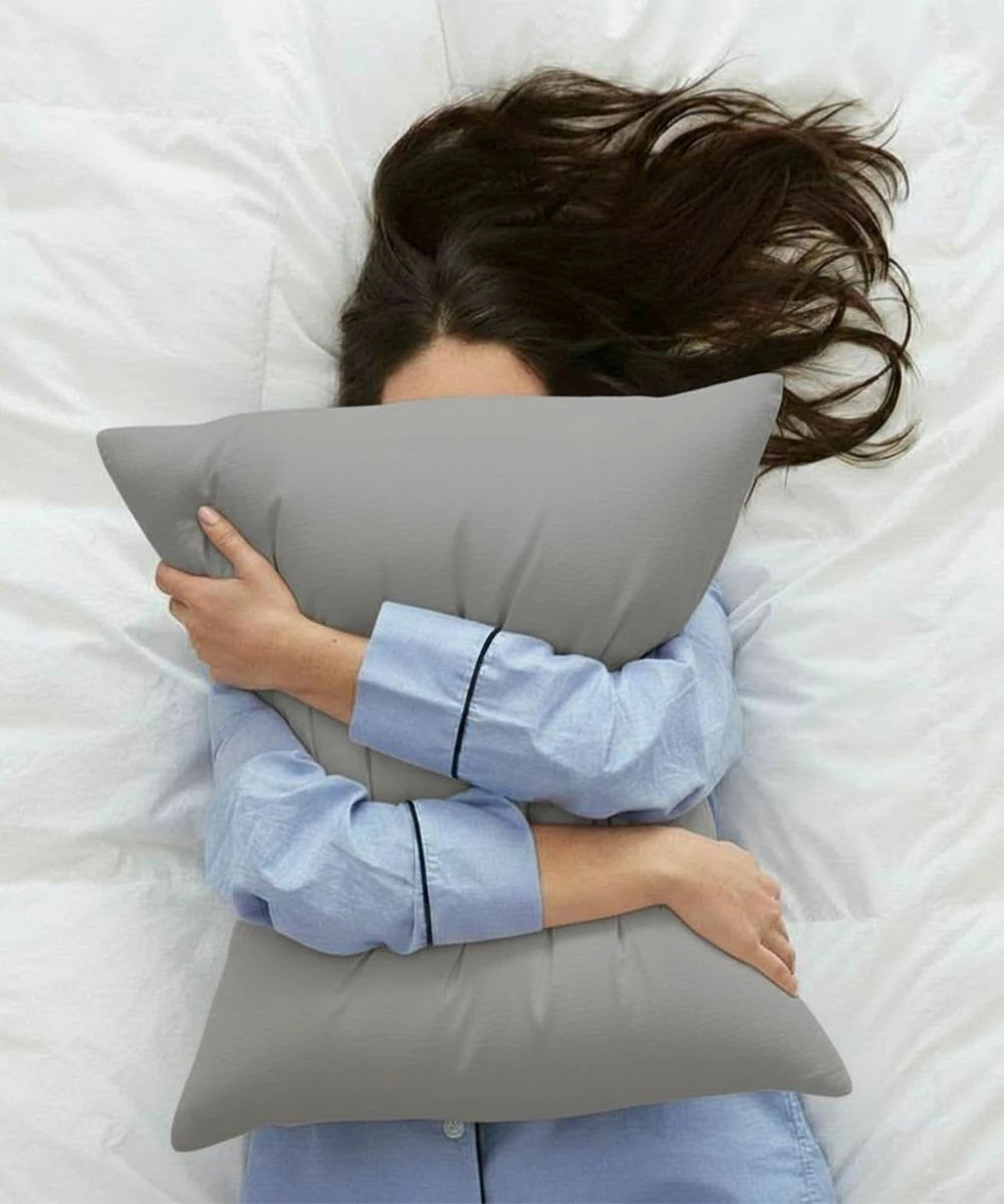 Person lying on a bed with a moon mist pillow 