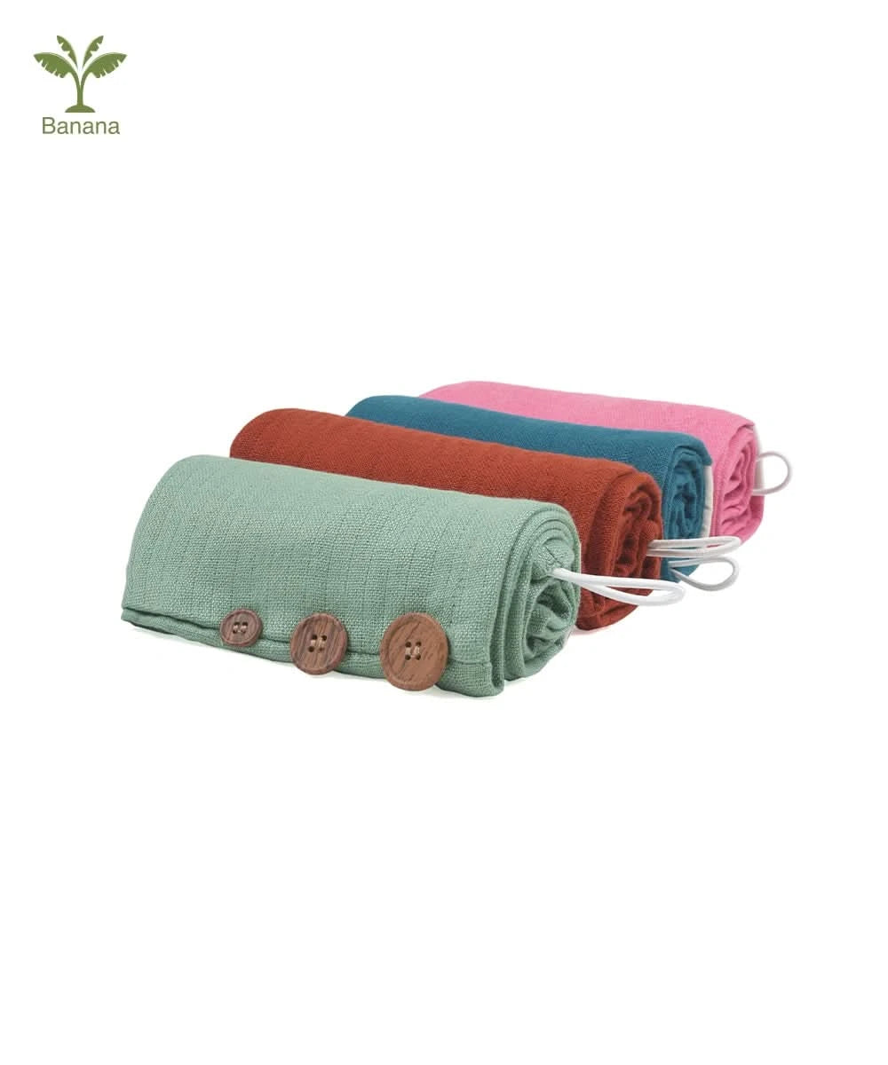 Four rolled-up towels in green, red, blue, and pink with wooden buttons on a white background.