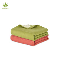 Two folded aluvera towels, one aloe green and one apricot brandy , on a white background.