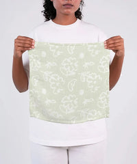 Person holding a light green fabric with white floral pattern against a white background