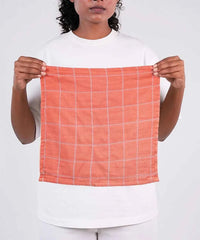 Person holding a orange checkered towel against a white background