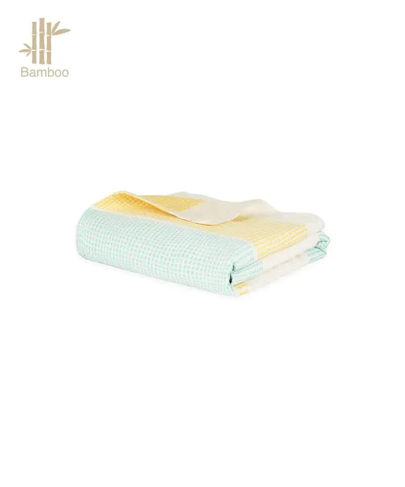 Folded bamboo towel with green and yellow pattern on a white background