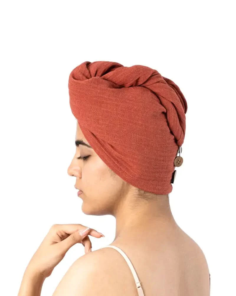 Woman wearing a terracotta hair towel with buttons on a white background
