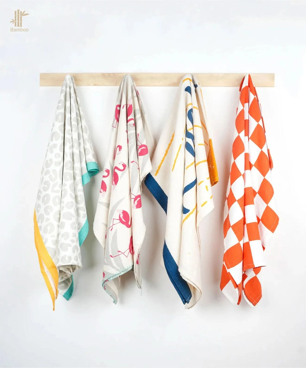 Four thirsty towels hanging on a wooden rod against a white background