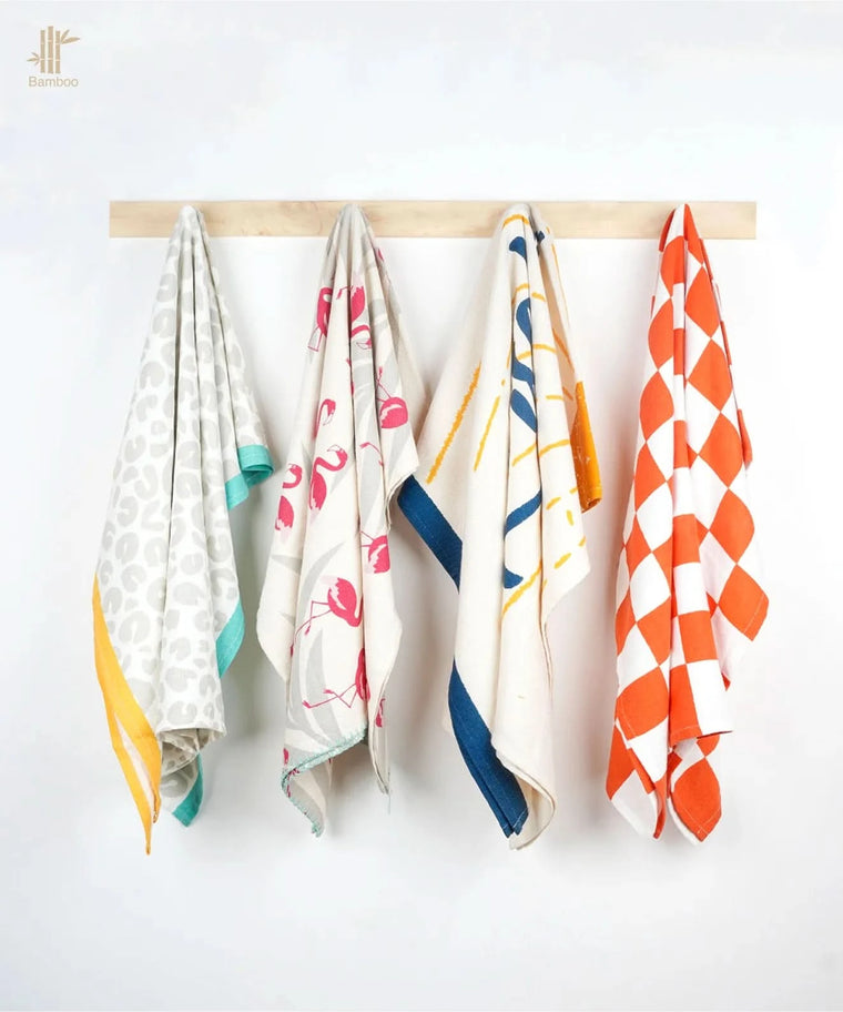 Four thirsty towels hanging on a wooden rod against a white background