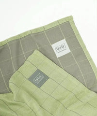 Two green textured towels with labels on a white background