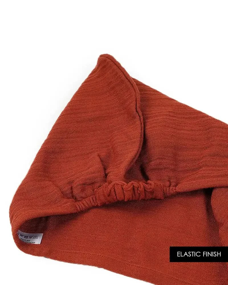 Close-up of a terracotta colored hair towel with an elastic finish on a white background