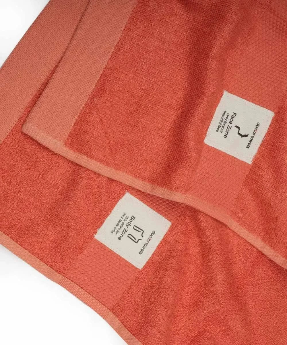 Two desert coral-colored towels with labels on a white background
