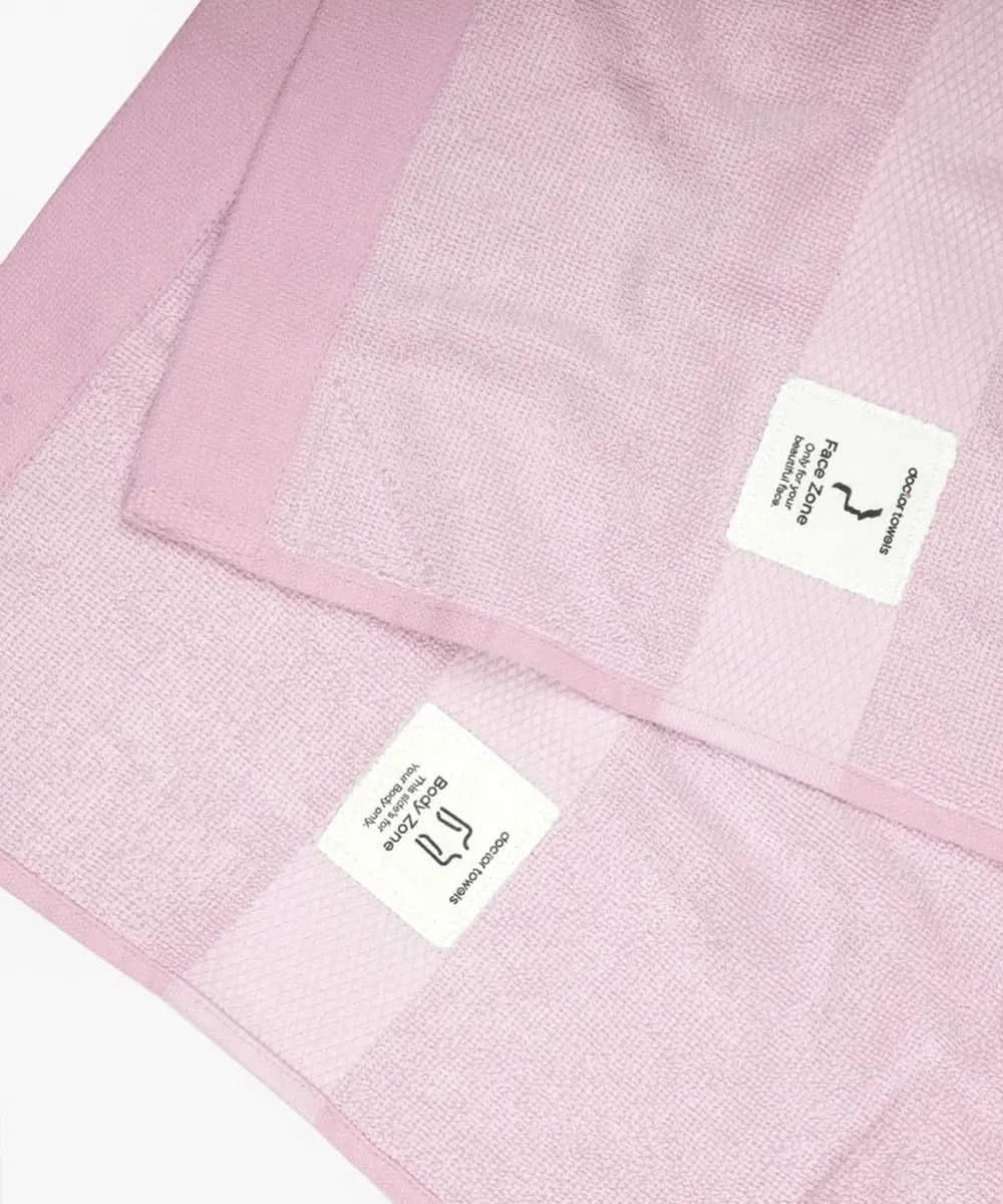 Close-up image of barely pink banana super light terry bath towel with labels on a white background