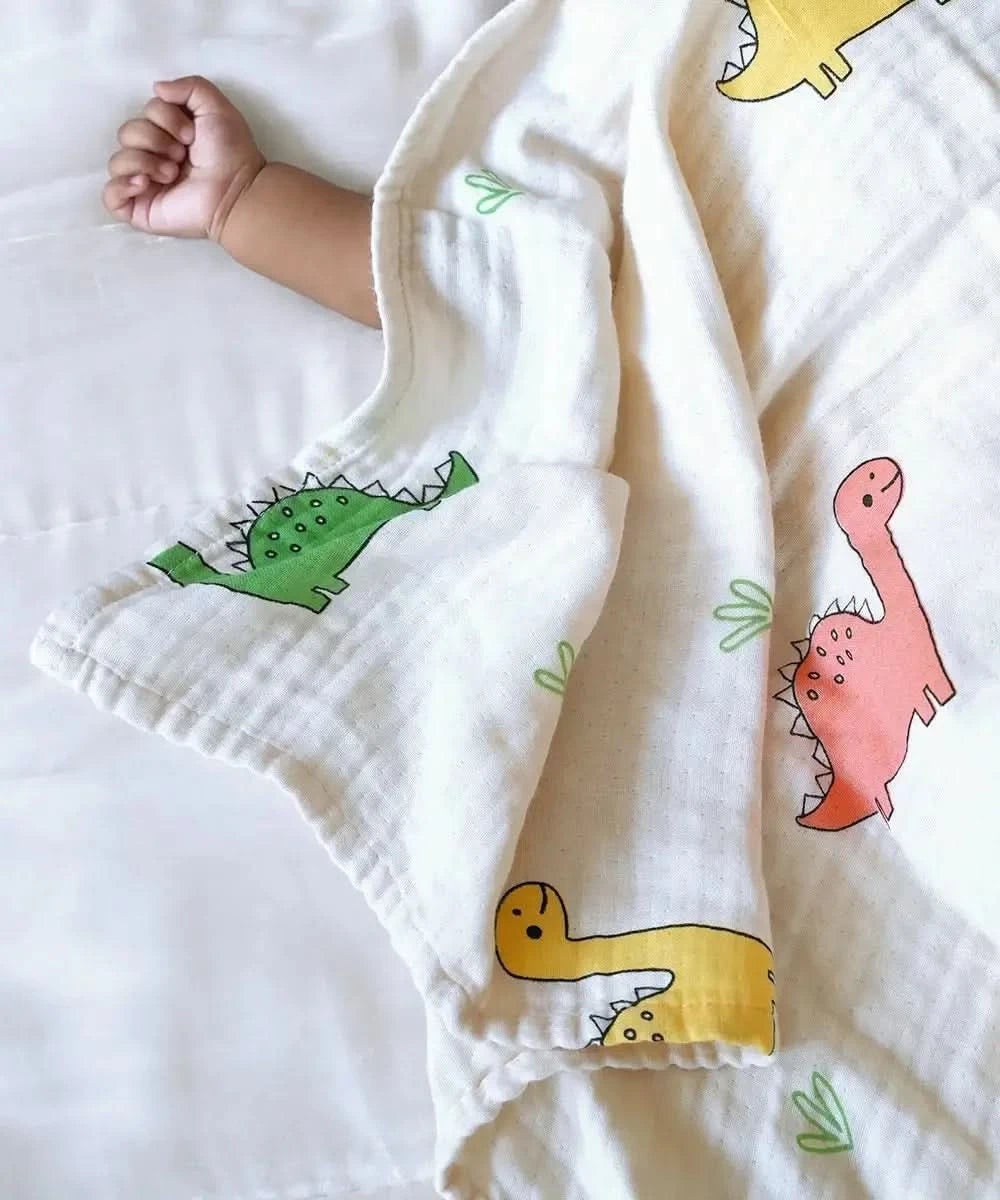 Baby wrapped in a bamboo swaddle with colorful dinosaur patterns on a white background