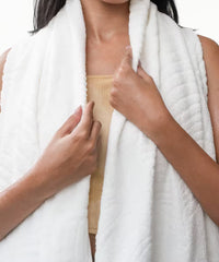 Person holding a white towel over their shoulders against a white background