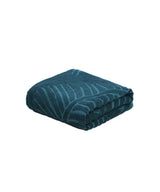 Folded teal towel with a leaf pattern on a white background