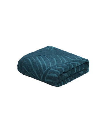 Folded teal towel with a leaf pattern on a white background