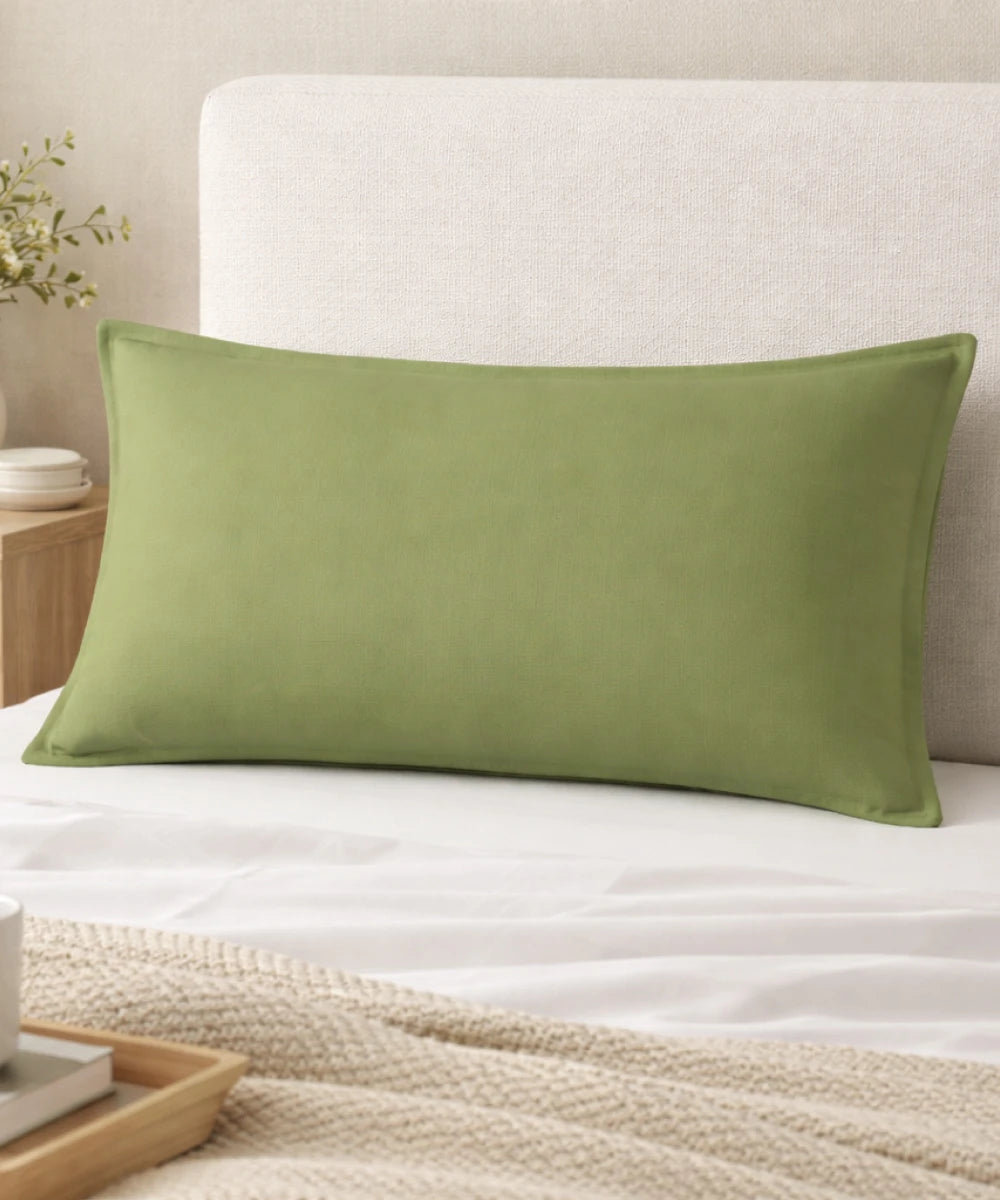 Aloe green pillow on a bed with a neutral headboard