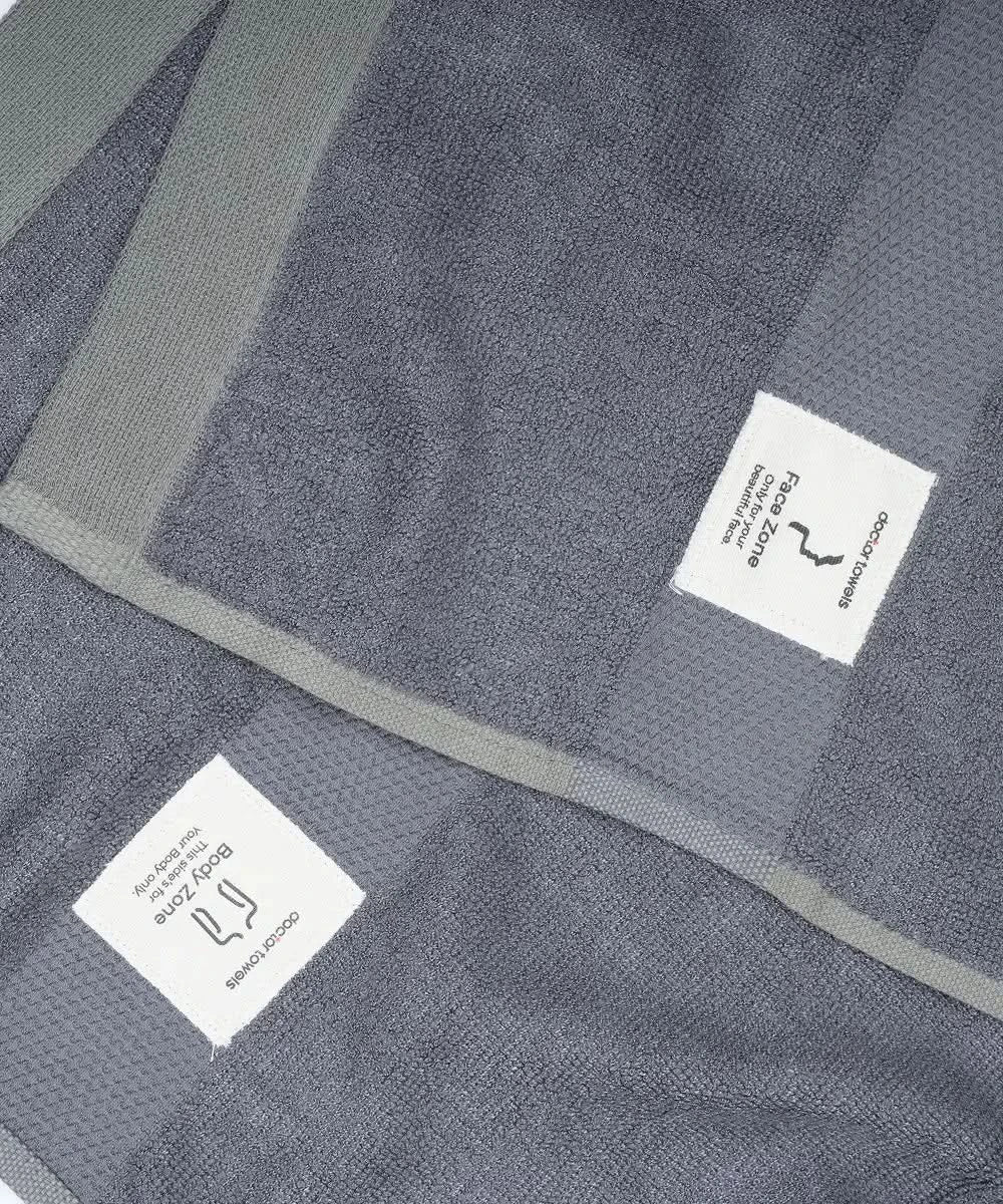 Close-up image of shadow grey banana super light terry bath towel with textured weave and Doctor Towels label - Dual zones - face side and body side