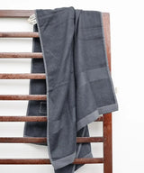 Gray towel draped over a wooden towel rack against a white background