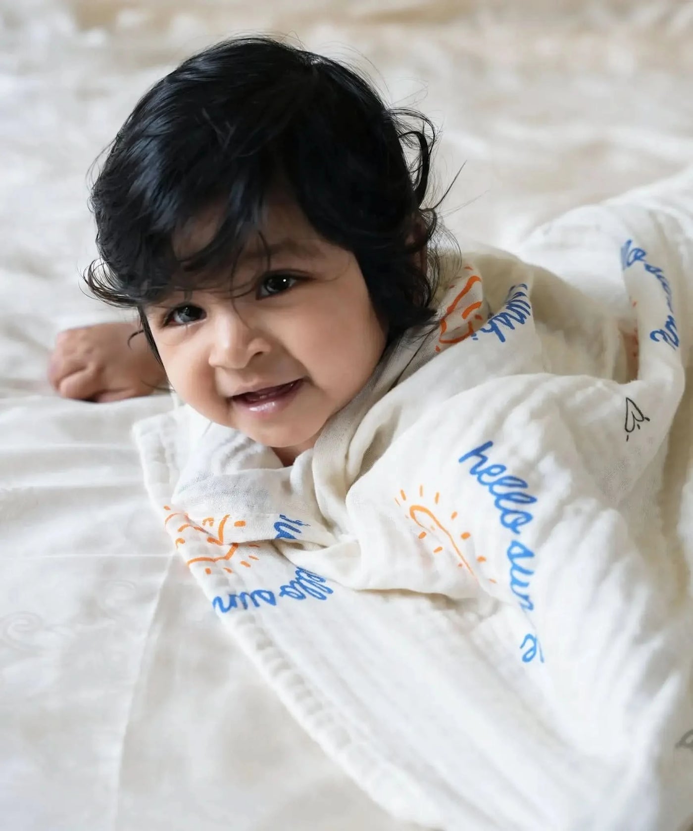 Child wearing a bamboo swaddle with colorful text and patterns on a light background
