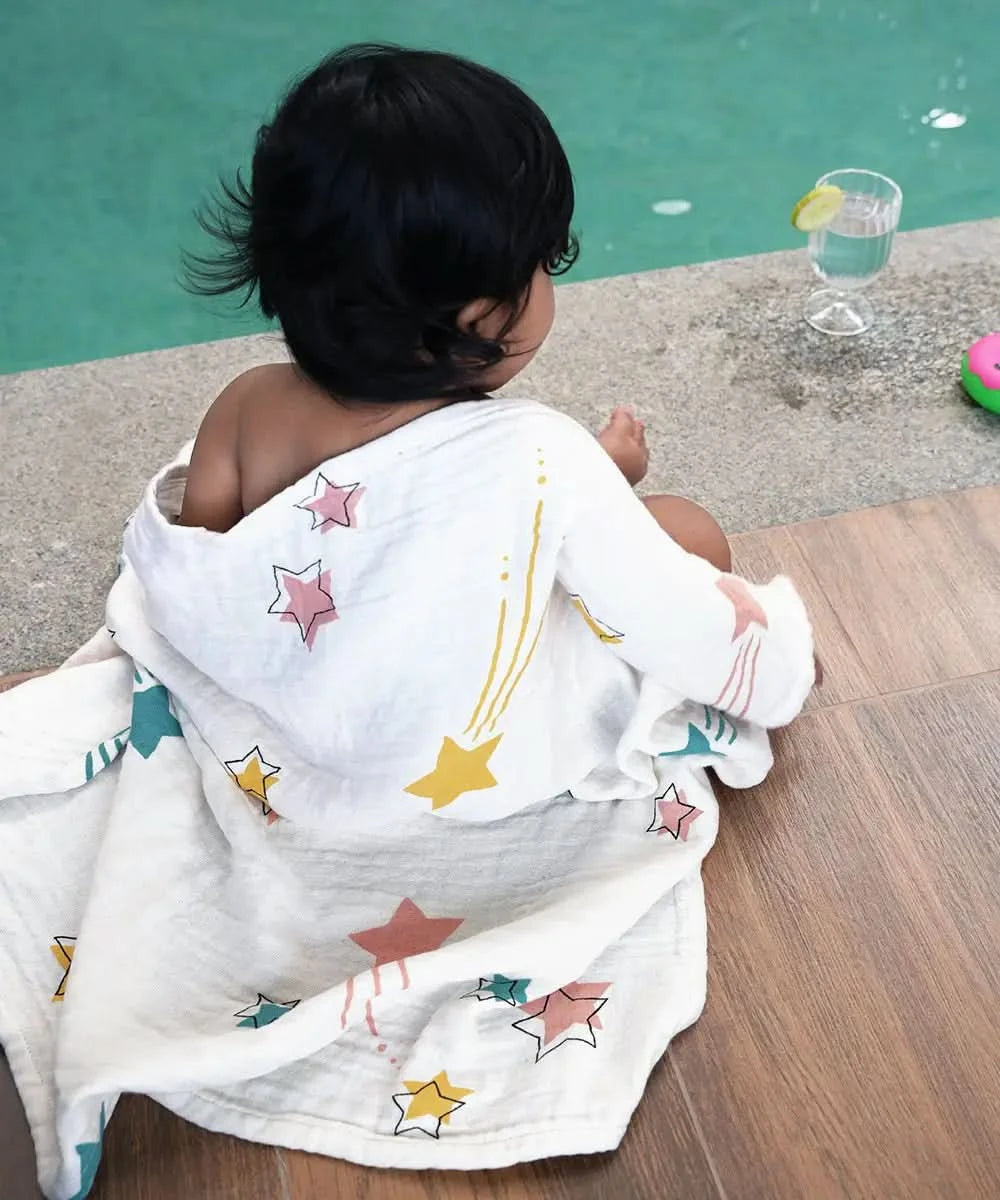 Child wrapped in a star-patterned towel by a poolside