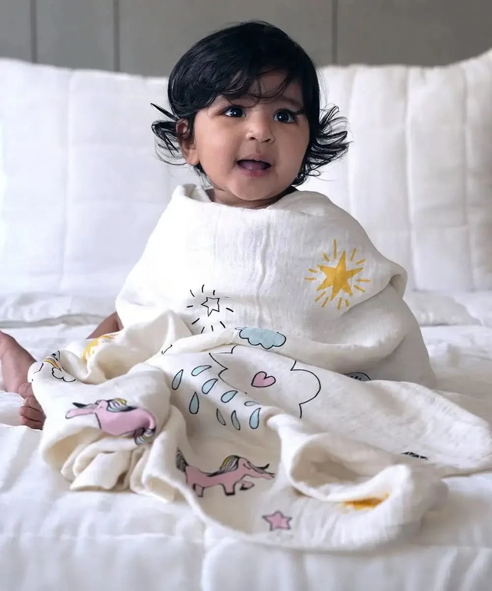 Child wrapped in a white blanket with colorful designs on a bed
