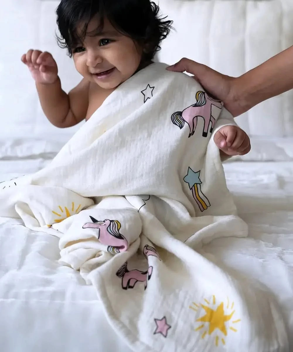 Child wrapped in a baby swaddle with colorful unicorn and star patterns on a white background